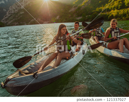 A group of friends enjoying fun and kayaking exploring the calm river, surrounding forest and large natural river canyons during an idyllic sunset. 121337027