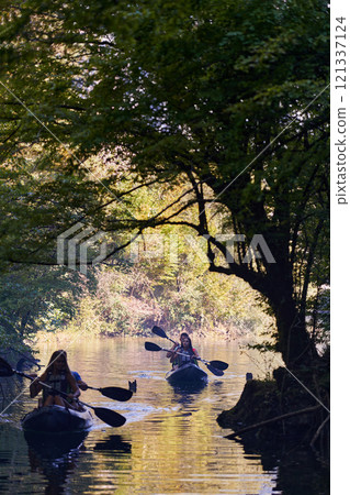 A group of friends enjoying having fun and kayaking while exploring the calm river, surrounding forest and large natural river canyons 121337124