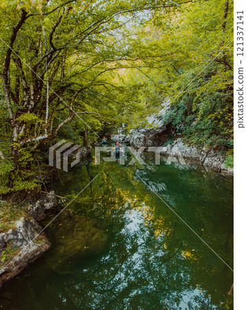 A group of friends enjoying having fun and kayaking while exploring the calm river, surrounding forest and large natural river canyons 121337141