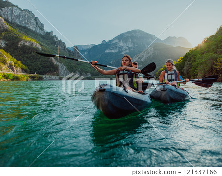 A group of friends enjoying fun and kayaking exploring the calm river, surrounding forest and large natural river canyons during an idyllic sunset. 121337166