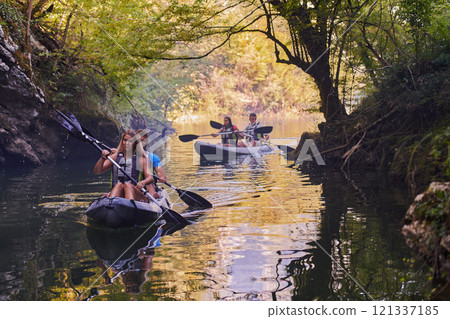 A group of friends enjoying having fun and kayaking while exploring the calm river, surrounding forest and large natural river canyons A group of friends enjoying having fun and kayaking while exploring the calm river, surrounding forest and large natural river canyons 121337185