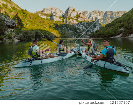 A group of friends enjoying having fun and kayaking while exploring the calm river, surrounding forest and large natural river canyons A group of friends enjoying having fun and kayaking while exploring the calm river, surrounding forest and large natural river canyons 121337197