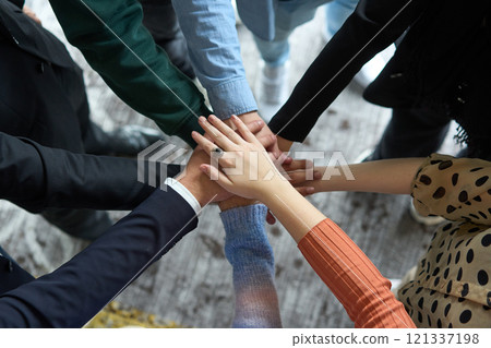 A top view of business people joining hands in a circle, symbolizing unity, collaboration, and shared success in the workplace 121337198