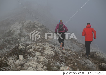trail running couple man and woman running on a mountain path 121337243