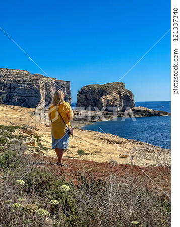Woman stand and look at Dwejra Bay, Gozo Island, Malta Woman stand and look at Dwejra Bay, Gozo Island, Malta 121337340