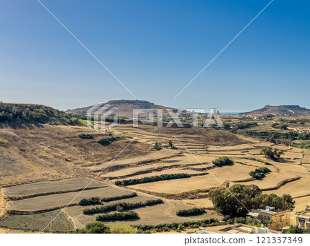 Hills with church visible in distance - panoramic view from the Old medieval citadel, Gozo island Hills with church visible in distance - panoramic view from the Old medieval citadel, Gozo island 121337349