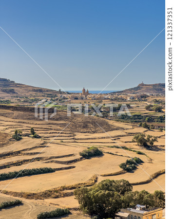 Hills with church visible in distance - panoramic view from the Old medieval citadel, Gozo island 121337351