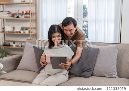 Retired Couple Enjoying Relaxation and Comfort in Their Cozy Living Room with Modern Decor and Warm Atmosphere 121338059