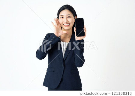 A young woman in a suit shouting while holding a smartphone 121338313