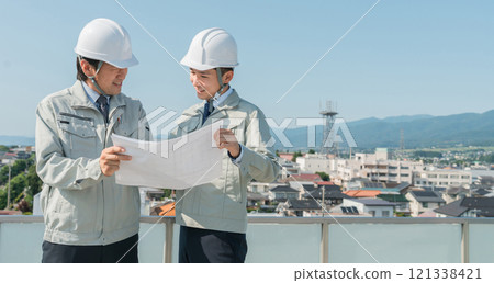 穿著工作服的工人在藍天下看藍圖(建築、建築、設計、房地產、土木工程、施工、現場監工) 穿著工作服的工人在藍天下看藍圖(建築、建築、設計、房地產、土木工程、施工、現場監工) 121338421