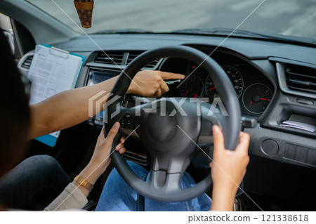 An instructor guides a student driver on the importance of dashboard controls 121338618