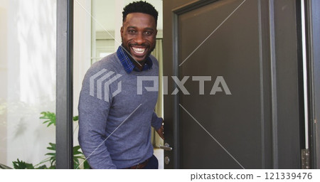 Smiling man opening front door, welcoming guests into cozy home Smiling man opening front door, welcoming guests into cozy home 121339476