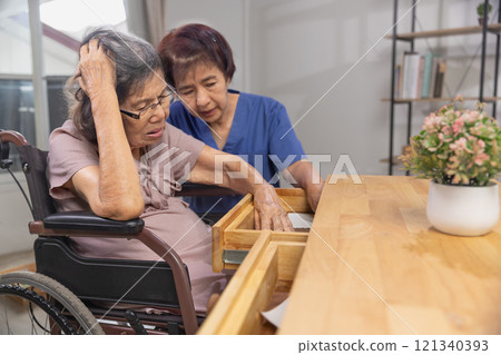 Caregiver help elderly woman looking for something that she forgot it in drawers. 121340393