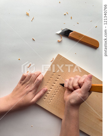 Intricate wood carving with hand tools on light surface Intricate wood carving with hand tools on light surface 121340766