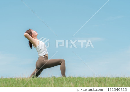 年輕的亞洲女性在藍天下做瑜珈、皮拉提斯和伸展運動 年輕的亞洲女性在藍天下做瑜珈、皮拉提斯和伸展運動 121340813