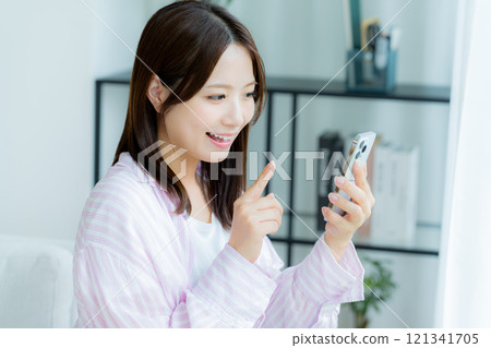 在房間裡操作智慧型手機的年輕女子 121341705