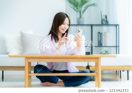 在房間裡操作智慧型手機的年輕女子 121342251