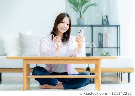 在房間裡操作智慧型手機的年輕女子 121342252