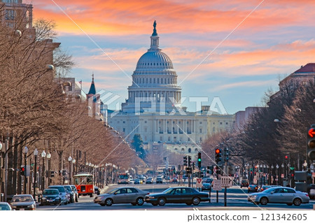 The US Capitol Dome overlooking a busy street with traffic under a colorful sunset in Washington DC 121342605