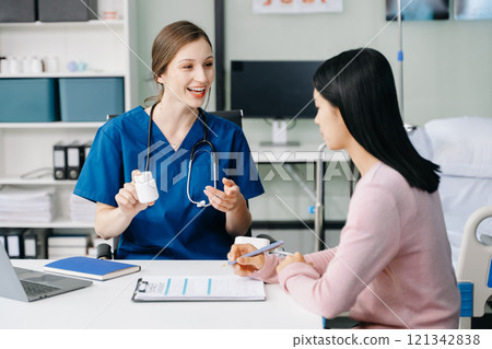 Female doctor using clipboard is delivering great news talk discuss results or symptoms with female patient in clinic or hospital Female doctor using clipboard is delivering great news talk discuss results or symptoms with female patient in clinic or hospital 121342838