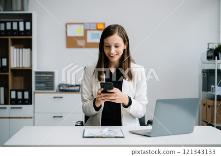 Young woman using laptop and tablet while sitting at her working place. Concentrated at work. 121343133