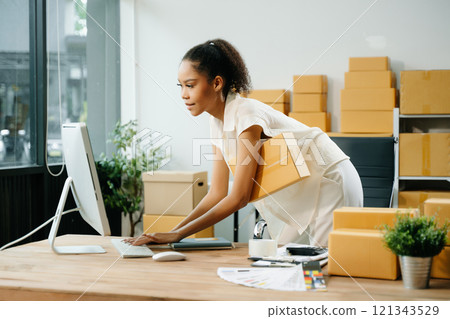 Young business owner woman prepare parcel box and standing check online orders for deliver 121343529