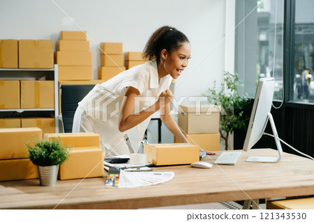 Young business owner woman prepare parcel box and standing check online orders for deliver 121343530