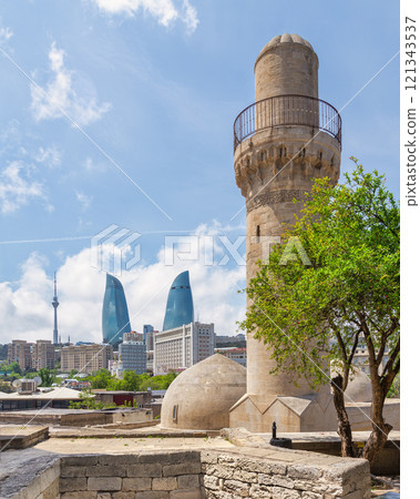 Minaret of Shah Mosque and Flame Towers contrasting the skyline of Baku, Azerbaijan 121343537