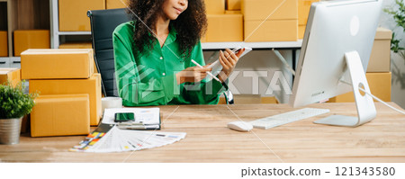 Young business owner woman prepare parcel box and standing check online orders for deliver 121343580
