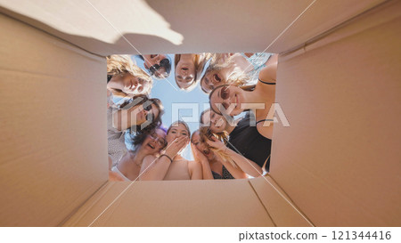 Excited high school students peering into a cardboard box, experiencing a delightful surprise during their summer break 121344416