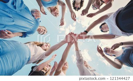 Group of young friends is joining hands in a circle outdoors, showing their unity and support for each other. Group of young friends is joining hands in a circle outdoors, showing their unity and support for each other. 121344427