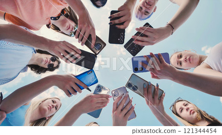 Young women friends capturing moments with their smartphones in a circle under a clear blue sky Young women friends capturing moments with their smartphones in a circle under a clear blue sky 121344454