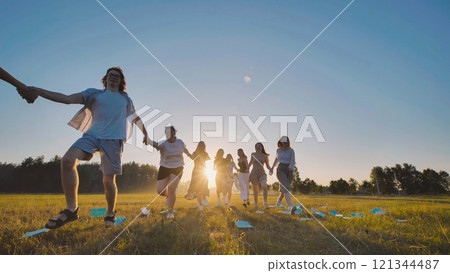 Joyful high school graduates running together in a field at sunset, rejoicing in their accomplishments and newfound freedom 121344487