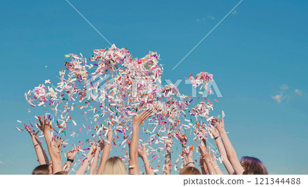Group of high school students throwing colorful confetti in the air celebrating graduation under a bright blue sky Group of high school students throwing colorful confetti in the air celebrating graduation under a bright blue sky 121344488