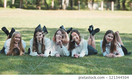Five happy students in white shirts and bow ties are lying on the grass in a park, enjoying a sunny day Five happy students in white shirts and bow ties are lying on the grass in a park, enjoying a sunny day 121344504