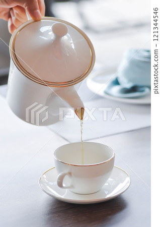 pouring tea , tea cup and tea pot or hot tea pouring tea , tea cup and tea pot or hot tea 121344546