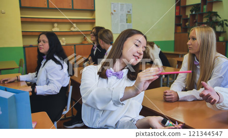 Schoolgirls wearing white shirts and bow ties are interacting during their first day of class in a classroom Schoolgirls wearing white shirts and bow ties are interacting during their first day of class in a classroom 121344547