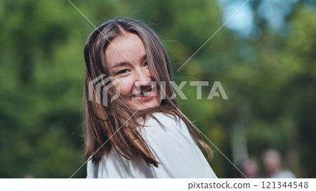 Happy student girl smiling and looking back in the park on her first day of school Happy student girl smiling and looking back in the park on her first day of school 121344548