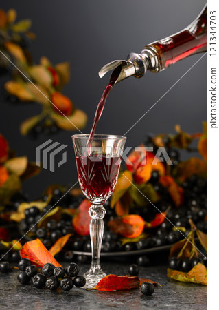 Black chokeberry liqueur and fresh berries on a black table. Black chokeberry liqueur and fresh berries on a black table. 121344703