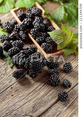 Ripe juicy blackberries with leaves on a wooden table. 121344709