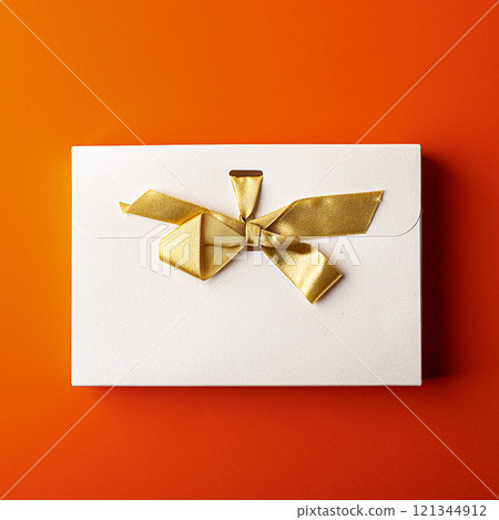 White gift box with gold ribbon isolated on orange background 121344912