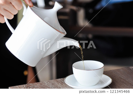 pouring tea , tea cup and tea pot or hot tea pouring tea , tea cup and tea pot or hot tea 121345466