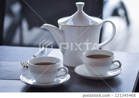 pouring tea , tea cup and tea pot or hot tea pouring tea , tea cup and tea pot or hot tea 121345468
