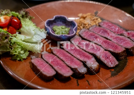 Medium rare sliced rib eye meat served on plate with vegetable 121345951