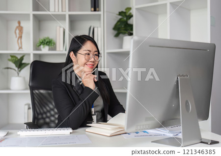 Middle-aged Business Woman Doing Paperwork and Working on Computer in Modern Office Setting 121346385