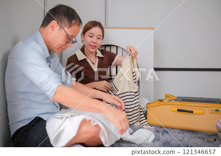 Father and Daughter Folding Clothes Together and Packing Them into a Suitcase for a Family Trip Father and Daughter Folding Clothes Together and Packing Them into a Suitcase for a Family Trip 121346657
