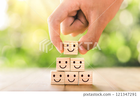 Customer service evaluation and satisfaction survey concepts. The client's hand picked the happy face smile face icon symbol on wooden cube. Customer service evaluation and satisfaction survey concepts. The client's hand picked the happy face smile face icon symbol on wooden cube. 121347291