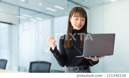 一位女商人看著電腦,做著拳頭泵 一位女商人看著電腦,做著拳頭泵 121348138