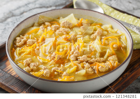 Egg Roll Soup combines ground meat, cabbage and a rich broth with ginger, garlic, and soy sauce for a savory, hearty meal closeup on the baking dish. Horizontal 121348281