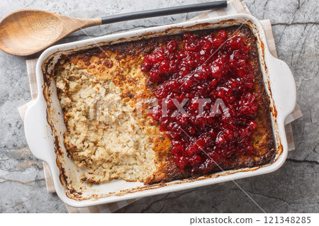 Spicy sweet Maksalaatikko creamy rice liver casserole served with cranberry jam close-up in baking dish. Horizontal top view 121348285